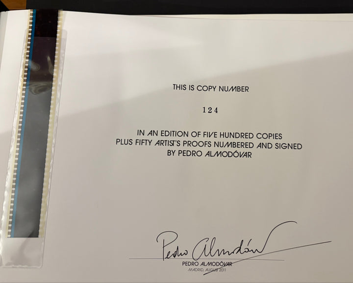 A white paper copy of a document or certificate with printed text and a signature, photographed inside a black folder or binder with a clear protective sleeve.